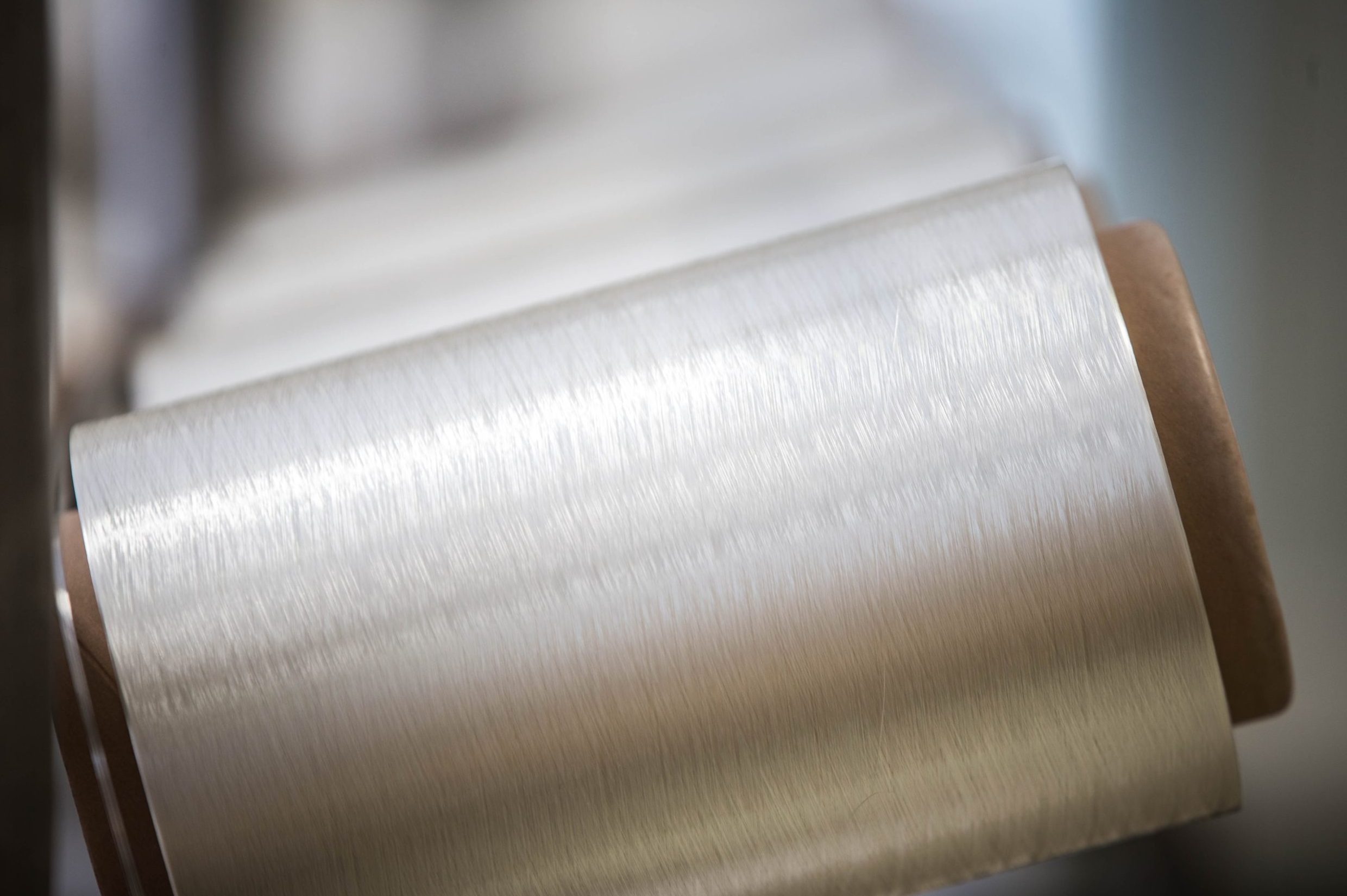 Close-up of spools of shiny silver thread positioned in a row, showcasing their smooth texture and metallic sheen.